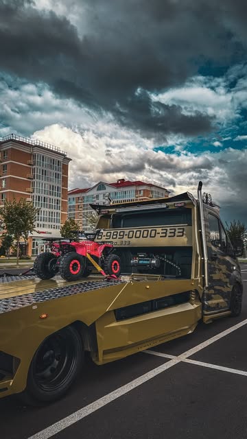 Красный квадроцикл на платформе эвакуатора